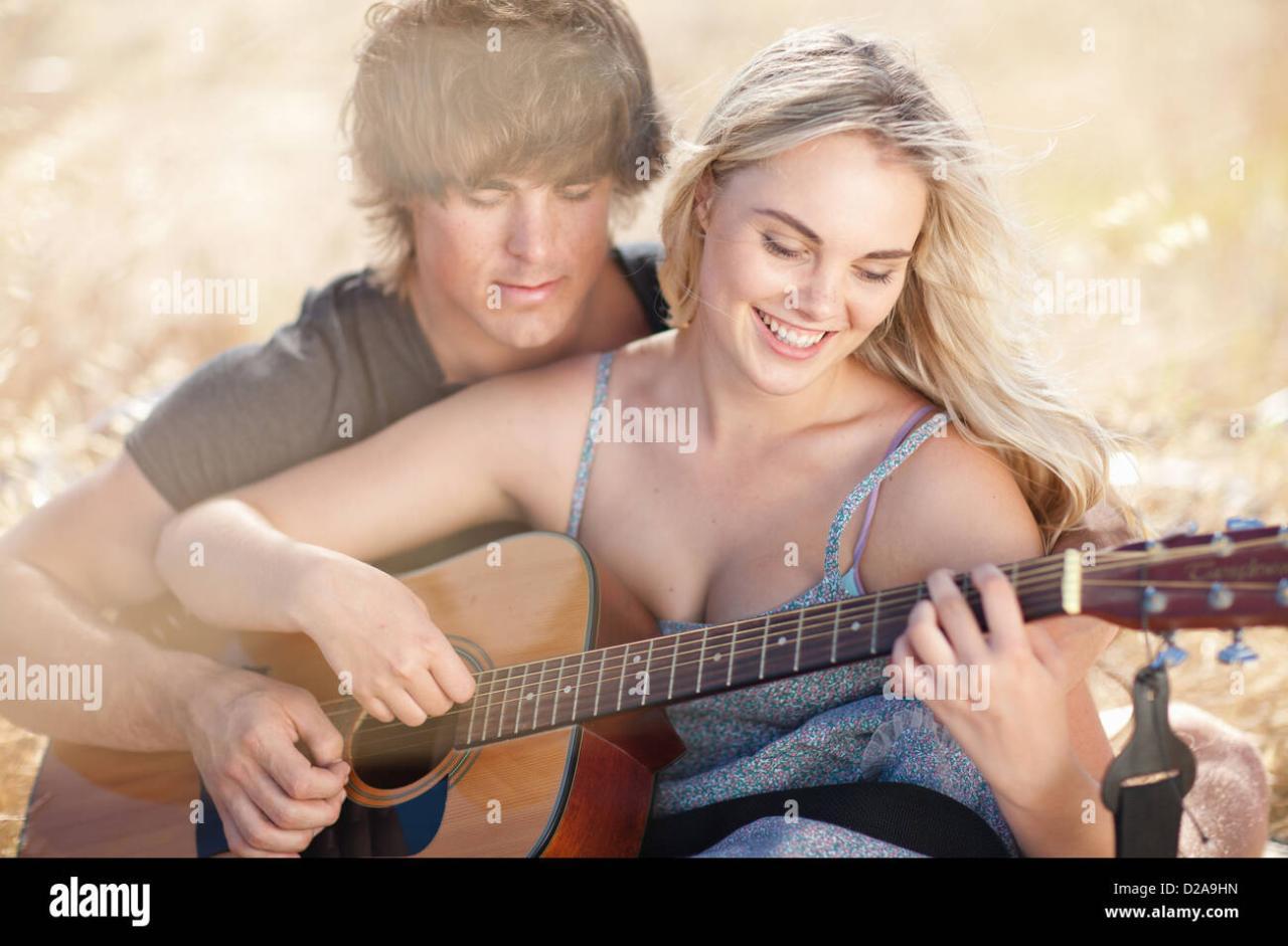 Group of happy friends with guitar. While one of them is playing guitar ...